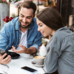 Gäste planen mit Guide am Smartphone eine private Stadtführung in Berlin im Café.