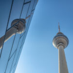 Berlin TV Tower reflected in a modern glass façade at Alexanderplatz.