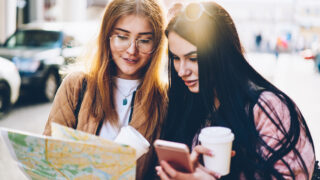 Stadtführer & Reisende planen mit Stadtplan und Smartphone eine private Stadtführung in Berlin – individuell.